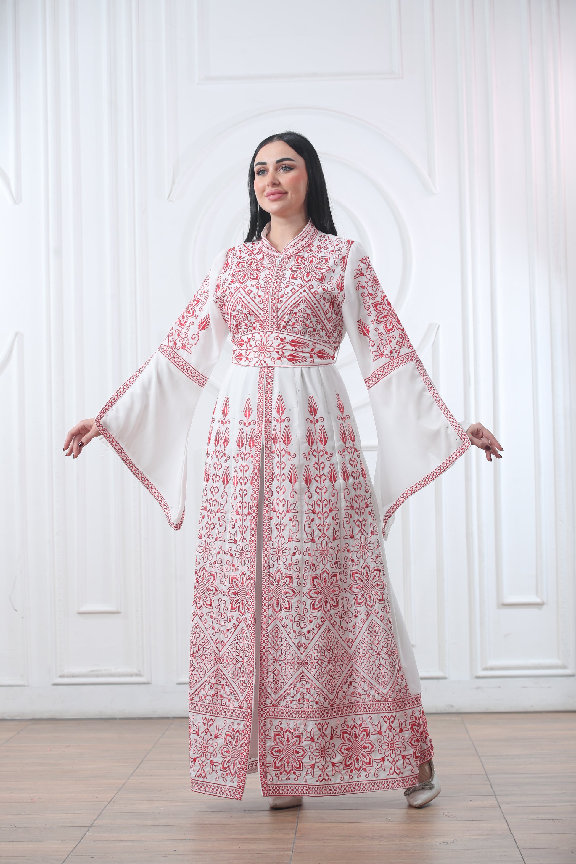 Woman wearing a white Palestinian thobe with red traditional embroidery, celebrating heritage