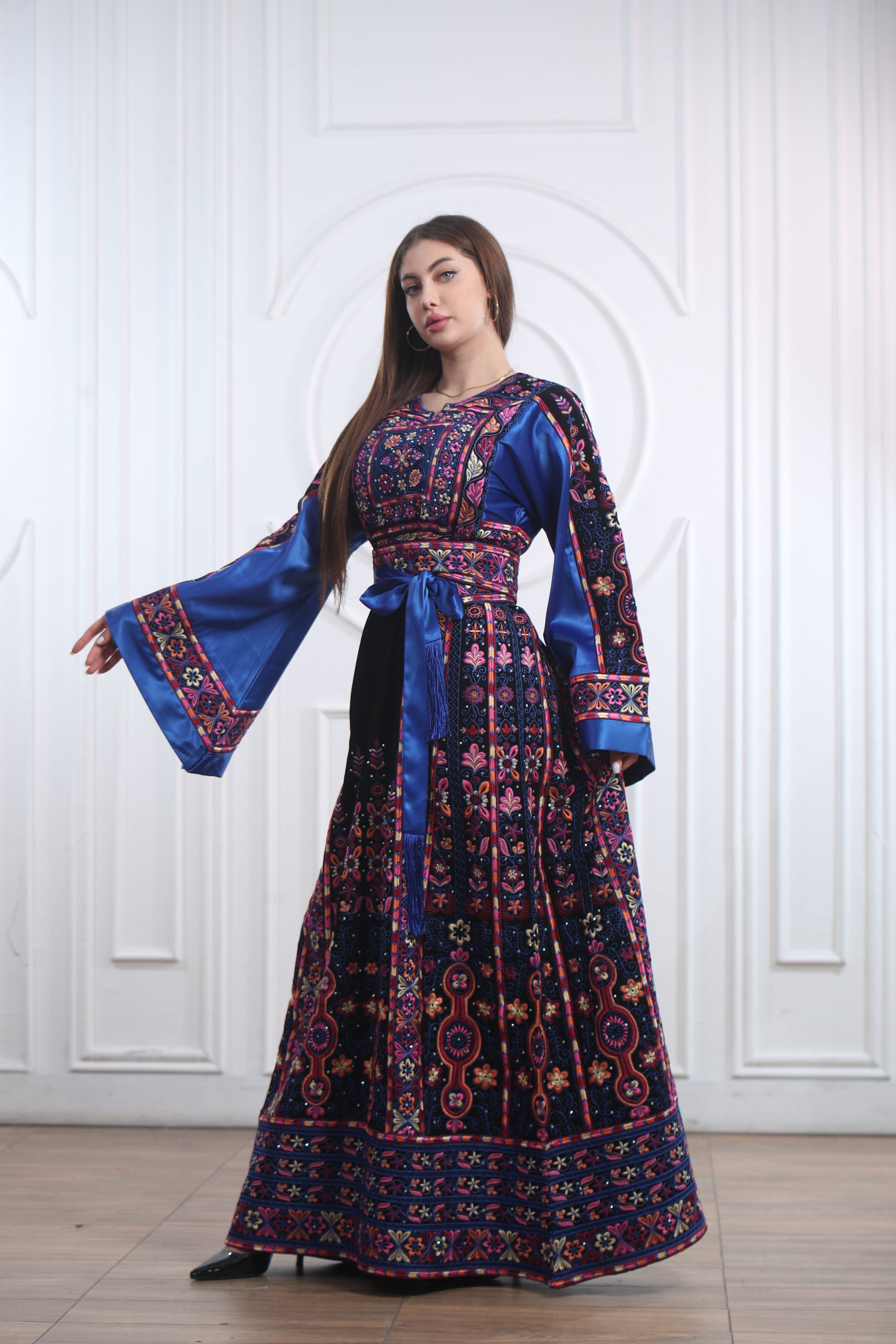 Woman wearing a blue Palestinian embroidered thobe with floral patterns, celebrating heritage